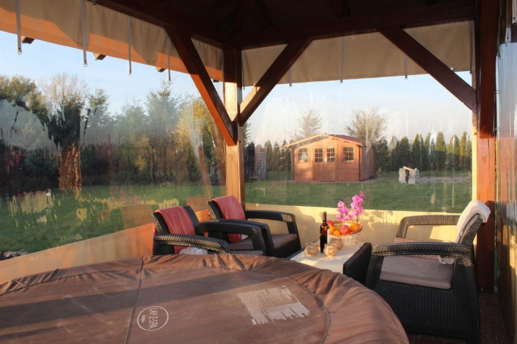 Przeźroczysta plandeka na wymiar osłaniająca drewnianą altanę z meblami ogrodowymi i jacuzzi Lay-Z-Spa