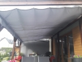 Vela ombreggiante grigia impermeabile estensibile 2,5x3 m montata su una pergola in legno sopra il terrazzo