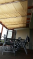 Vela ombreggiante premium impermeabile e retrattile 2,5x3 m installata sotto la copertura del terrazzo con mobili da relax