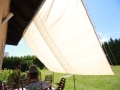 Vela ombreggiante da giardino beige estensibile Premium a copertura di una terrazza con mobili da giardino e barbecue
