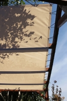 Voile d'ombrage beige HDPE sur mesure montée sur une pergola en bois avec des cordes élastiques
