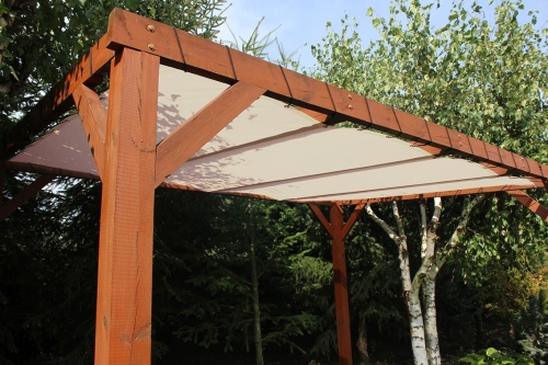 Voile d'ombrage beige en HDPE monté sur une pergola en bois dans un jardin.