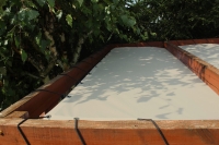 Voile d'ombrage HDPE beige clair sur mesure montée sur une structure de pergola en bois près d'un arbre