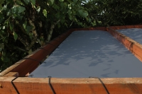 Voile d'ombrage HDPE grise sur mesure montée sur une structure en bois à l'aide de cordes élastiques