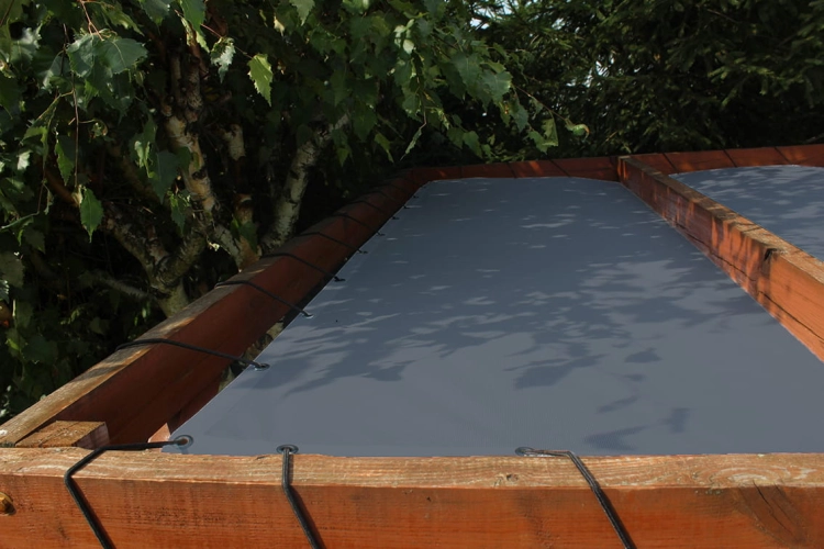 Voile d'ombrage HDPE grise sur mesure montée sur une structure en bois à l'aide de cordes élastiques