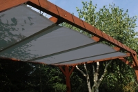 Voile d'ombrage gris en HDPE sur mesure, monté sur une pergola en bois dans un jardin