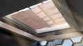 Protecție solară bej la comandă montată pe un luminator mare într-un interior modern