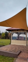 Voile d'ombrage triangulaire imperméable en PVC sur mesure installée sur une terrasse près d'un gazebo