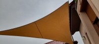 Voile d'ombrage triangulaire imperméable en PVC sur mesure montée au mur du bâtiment