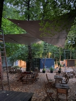 Voile d'ombrage triangulaire imperméable en PVC au-dessus de tables en bois dans un jardin de restaurant en automne