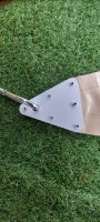 Angle d'une voile d'ombrage triangulaire en PVC avec attache métallique et mousqueton sur fond d'herbe