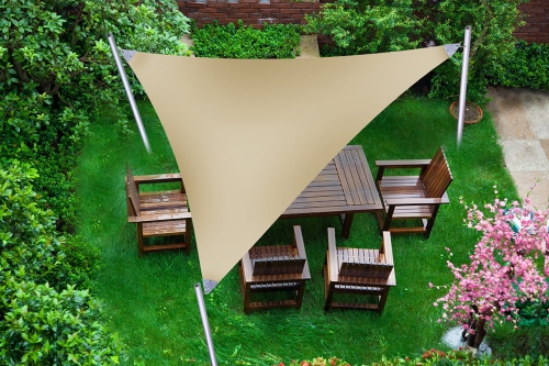 Voile d'ombrage triangulaire beige imperméable au-dessus de meubles de jardin en bois sur la pelouse