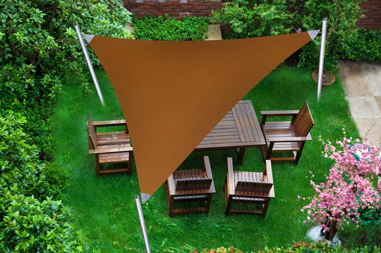 Voile d'ombrage triangulaire imperméable en PVC installée au-dessus de meubles de jardin en bois sur une pelouse