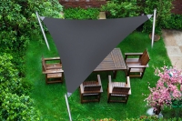 Voile d'ombrage triangulaire grise dans un jardin au-dessus d'un salon de jardin en bois sur l'herbe