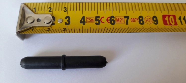 Conector negro para tubos de aluminio junto a una cinta métrica sobre fondo blanco