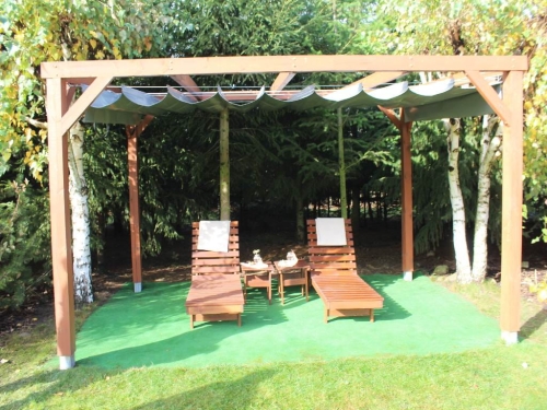 Store romain de terrasse en PVC imperméable sur mesure installé sous une pergola en bois avec transats de jardin