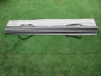 Store romain de terrasse gris imperméable en PVC avec fixations noires, plié sur un fond vert