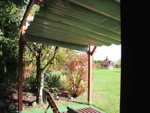 Store romain de terrasse gris imperméable en PVC monté sur une pergola en bois dans un jardin