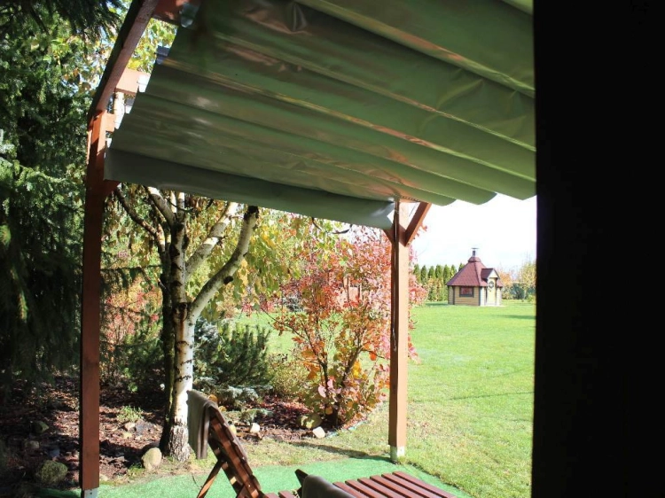 Store romain de terrasse gris imperméable en PVC monté sur une pergola en bois dans un jardin