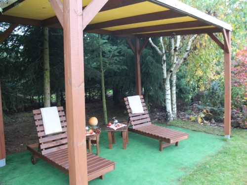 Toiture de terrasse PVC sur mesure toutes saisons sur des transats en bois au jardin