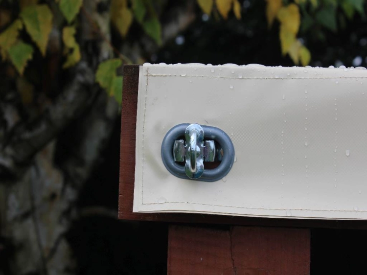 Gros plan sur un fermoir rotatif en acier fixant un toit de terrasse blanc en PVC quatre saisons à une structure en bois