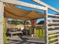 Vela da giardino beige impermeabile e retrattile 2,5x3 m montata su una pergola in legno sopra i mobili da giardino