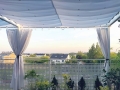 Vela ombreggiante bianca impermeabile ed estensibile 2,5x3 m Premium su una terrazza con tende e ghirlande luminose