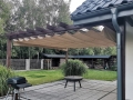 Rulou roman pentru terasă bej 2,5x4 m montat sub o pergolă maro pe o terasă modernă cu grădină
