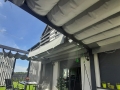 Rulou roman de terasă Premium gri cu dimensiuni de 2,5x4 m montat pe o pergolă modernă la o casă cu grădină