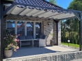 Rulou roman de terasă pentru protecție solară 2,5x4 m montat sub o structură de pergolă neagră pe o terasă cu mobilier de grădină