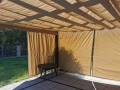 Rulou roman de terasă Premium bej montat pe pergolă, protecție solară deasupra unei terase din piatră