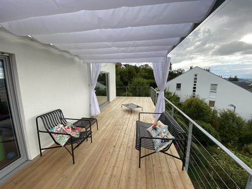 Store romain de terrasse blanc 3x3 m installé sous un toit sur une terrasse moderne avec parquet en bois et meubles