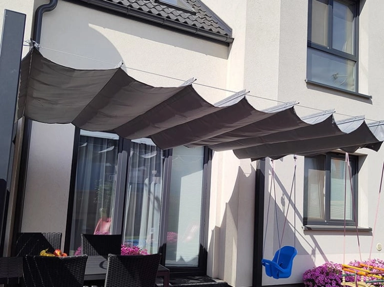 Store romain de terrasse imperméable 3x3 m gris, installé au-dessus d'un salon de jardin.