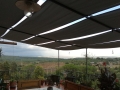 Bande de pergola Premium grise imperméable abritant une terrasse avec vue sur le paysage et la verdure