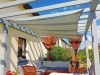 Vela ombreggiante impermeabile 4x4m montata sopra un terrazzo con mobili da giardino moderni