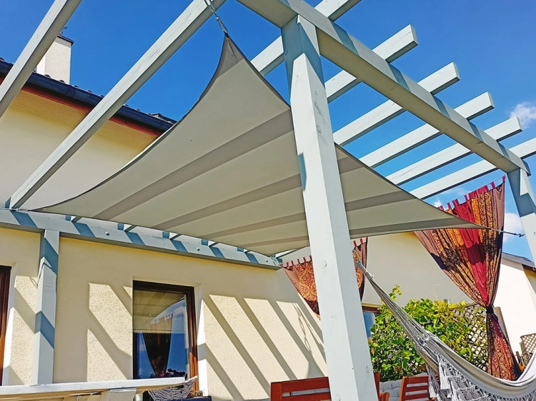 Toldo vela rectangular impermeable 3x4 m instalado sobre una terraza con pérgola blanca y hamaca
