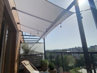 Voile d'ombrage imperméable blanche 3x4 m installée au-dessus d'une terrasse avec salon de jardin et éclairage d'ambiance