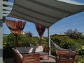 Grauer Sonnensegel 3x3 m über einem Holz-Gartenmöbel-Set auf der Terrasse