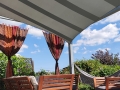 Toldo vela cuadrado impermeable 3x3 m Premium que sombrea una terraza con muebles y hamaca al fondo