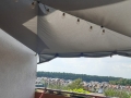 Toldo vela gris impermeable de 3x3 m montado sobre un balcón con guirnalda de luces