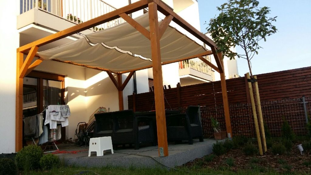 Beiges ausziehbares Sonnensegel montiert an einer Holz-Terrassenpergola mit Montageset an zwei Seilen