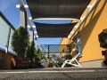 Prostokątny grafitowy żagiel przeciwsłoneczny 4x7 m z materiału HDPE zamontowany na tarasie nad krzesłem ogrodowym