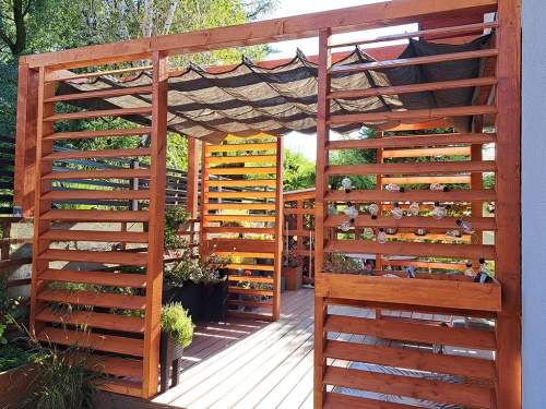 Braunes Raffrollo für die Terrasse aus HDPE-Material an einer Holzpergola im Garten montiert