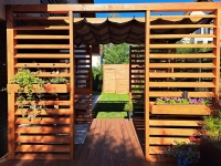 Braunes Raffrollo aus HDPE als Sonnenschutz an einer hölzernen Terrassenpergola im Garten montiert