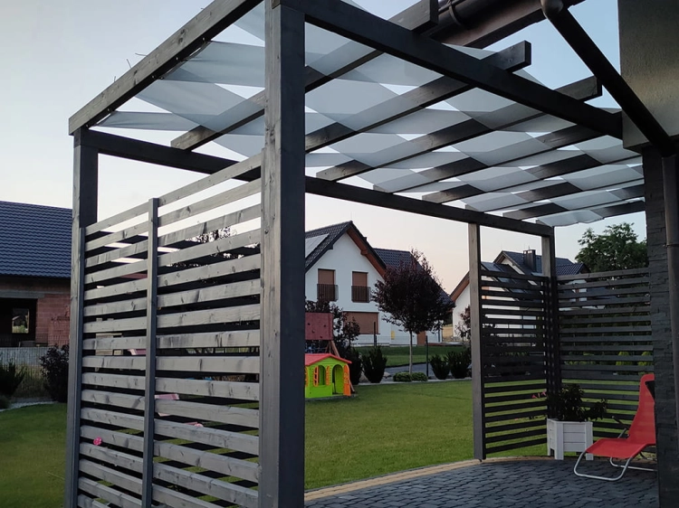 Bande pare-soleil blanche entrelacée entre les chevrons d'une pergola de jardin moderne sur une terrasse