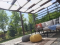 Witte schaduwbaan gemonteerd op een houten pergola boven het terras met tuinmeubelen