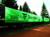 Zelená tenisová clona s logom Tecnifibre, zástena na mieru namontovaná na plote antukového kurtu