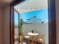 Voile d'ombrage imperméable blanche sur mesure installée au-dessus d'une terrasse avec meubles de jardin et cactus