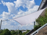 Wit rechthoekig schaduwdoek voor balkon, gemonteerd op masten bij het dak met uitzicht op de stadspanorama