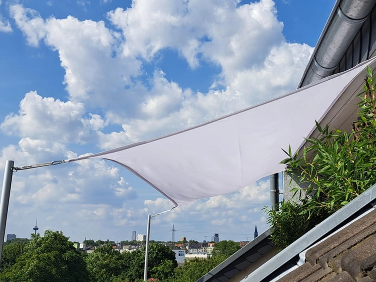 Voile d'ombrage rectangulaire blanche pour balcon, montée sur des mâts près du toit avec vue sur le panorama de la ville